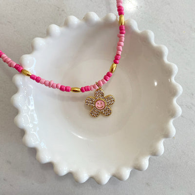 Collar Jazmin color rosa con dije de flor con cara feliz en oro laminado de 18K y zirconias